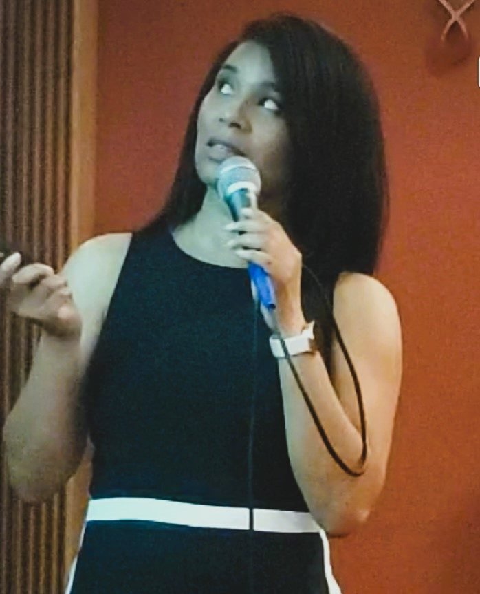 KaTrina Samuels-Garrison speaking with a microphone at a live event